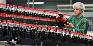 Fabrikarbeiter kontrolliert Cola-Flaschen