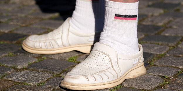 Füße eines Pegida-Teilnehmers in weißen Schuhen und Socken mit der Deutschland-Fahne