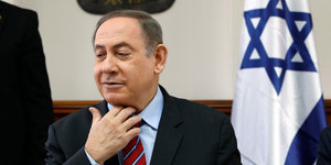 Israels Ministerpräsident Netanjahu lächelt süffisant und lockert sich die Krawatte
