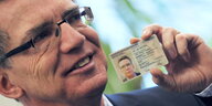 Bundesinnenminister Thomas de Maiziere hält seinen Ausweis in der Hand
