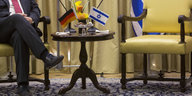 Sigmar Gabriel sitzt auf einem Stuhl, der Stuhl neben ihm ist leer. Im Hintergrund deutsche und israelische Fahnen