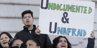 Eine Frau hält ein Schild hoch auf dem auf Englisch "Undokumentiert und furchtlos" steht