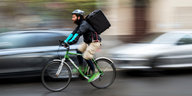 Ein Fahrrad-Essenslieferant fährt mit hoher Geschwindigkeit auf einer Straße