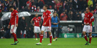 Nasse Spieler des FC Bayern stehen mit Münchner Stadion