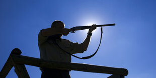 Silhouette eines Jägers mit seinem Gewehr im Anschlag