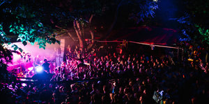 Blick auf eine Menschenmenge vor einer Outdoor-Konzertbühne bei Nacht