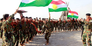 Peshmerga-Kämpfer beim Aufmarsch mit der Flagge Kurdistans