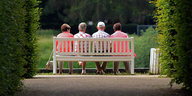 Mehrere ältere Menschen sitzen auf einer Parkbank