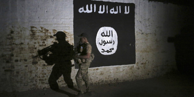 Ein Soldat in einem Tunnel vor einer Wandmalerei der IS-Fahne