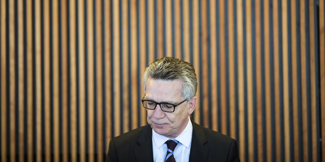 Thomas de Maizière vor einer Holzwand