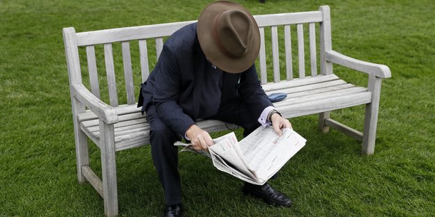 Ein Zeitungsleser auf einer Parkbank