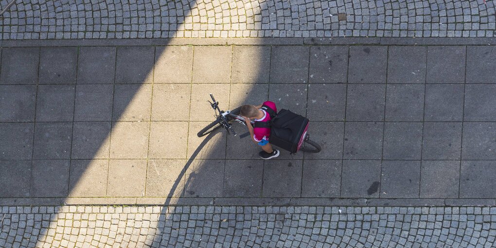 Ein Foodora-Fahrer guckt auf sein Smartphone