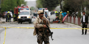 Ein afghanischer Sicherheitsmann steht mit Waffe im Arm hinter einem gelben Absperrband