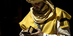 Mann in Ritterkostüm mit Smartphone in der Hand