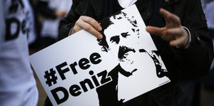 Jemand hält ein Plakat mit dem Gesicht von Deniz Yücel