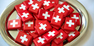 Kleine Schokoladentafeln eingewickelt in PApier mit der Schweizer Flagge