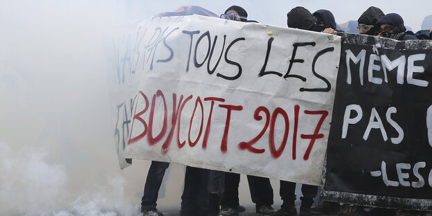 Demonstranten halten, eingehüllt in Rauch, ein Banner in die Höhe, auf dem "Boycott 2017" zu erkennen ist