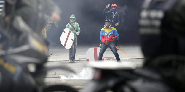 Vermummte Demonstranten und Polizisten in Caracas