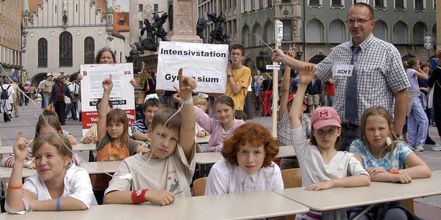 Mitten in der Münchner Innenstadt: Kinder, die am tropf hängen, sitzen an Schulbänken