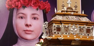 Das große Bild einer jungen Ordensfrau neben einem prunkvollen Altar