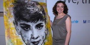 Nahid Shahalimi steht neben einem ihrer Werke, einem großformatigen Bild von Audrey Hepburn