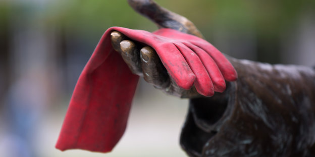 Die Hand einer Statue hält einen roten Handschuh