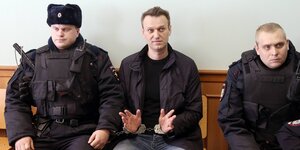 Zwei Polizisten und Nawalny in Handschellen