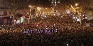 Eine demonstrierende Menschenmenge bei Nacht. In leuchtenden Buchstaben der Satz "No Fear".