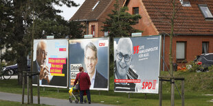 Eine ältere Frau betrachtet im Vorbeigehen ein großes Wahlplakat