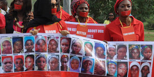 Demonstrierende tragen ein Transparent mit Bildern von den entführten Chibok-Mädchen
