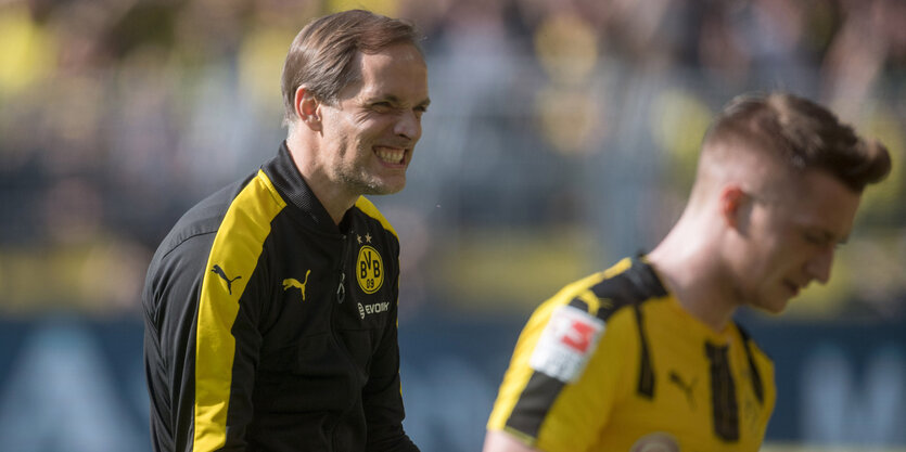 Thomas Tuchel steht schräg hinter einem Spieler und fletscht die Zähne