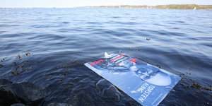 Ein Wahlplakat von Torsten Albig schwimmt im Wasser