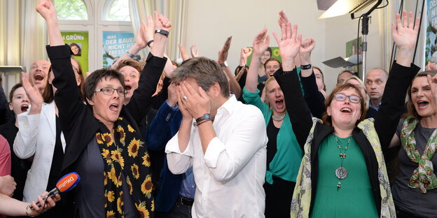 Robert Habeck schlägt sich bei der Wahlparty der Grünen in Kiel die Hände vors Gesicht, während um ihn herum alle jubeln