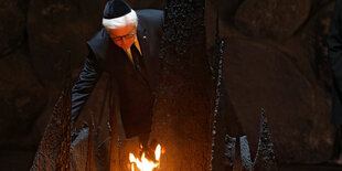 Steinmeier mit Kippa auf dem Kopf vor einer Flamme