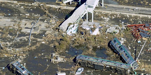 Ein zerstörter Bahnübergang und weggerissene Zugwaggons zeigen das Ausmaß der Zerstörung des Tsunamis 2011