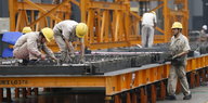 Beschäftigte eines Stahlwerks arbeiten an einer Stahlkonstruktion