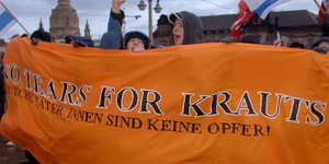 Menschen halten ein Transparent "No Tears for Krauts - Deutsche Täter_innen sind keine Opfer"