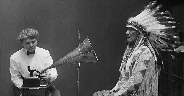 Ein Würdenträger der Native Americans vor einem Grammophon, das von einer Frau angekurbelt wird - Shcwarz-weiß-Foto
