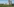 Eine grüne Wiesenlandschaft, in der zwei riesige Kühltürme herausragen