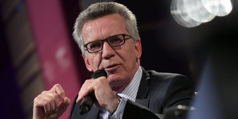 Porträt de Maizière, der in ein Mikrofon spricht