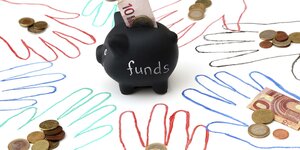 Ein Sparschwein mit der Aufschrift "Funds" steht in der Mitte des Bildes, drum herum sind Hände aufgemalt, auf denen echtes Geld liegt