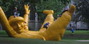Kinder spielen auf einer gelben Riesenpuppe