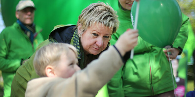 Ein Kind greift nach grünem Luftballon. Eine Frau, Sylvia Löhrmann, schaut zu Ein Kind greift nach grünem Luftballon. Eine Frau, Sylvia Löhrmann, schaut zu