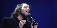 Der Sänger Salvador Sobral singt vor dunklem Hintergrund