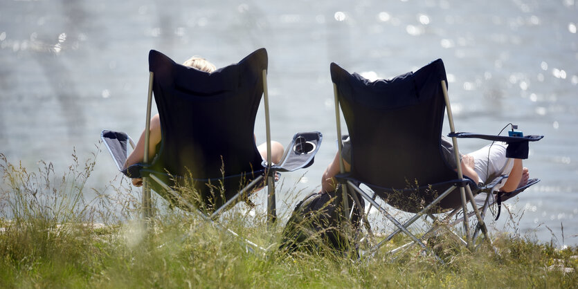 Zwei Frauen in Campingstühlen vor einem Fluss