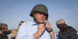 Dirk Niebel schnürt sich einen Stahlhelm fest