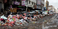 riesige Müllberge an rand einer schlammigen Straße in einer Stadt Straßenrand