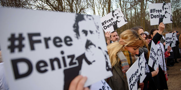 Menschen halten bei einer Kundgebung #FreeDeniz-Schilder hoch