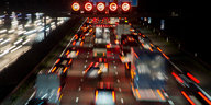 Auf einer Autobahn stauen sich Autos, rote Bremslichter leuchten und Hinweise zur Geschwindigkeitsbegrenzung