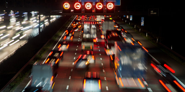 Auf einer Autobahn stauen sich Autos, rote Bremslichter leuchten und Hinweise zur Geschwindigkeitsbegrenzung